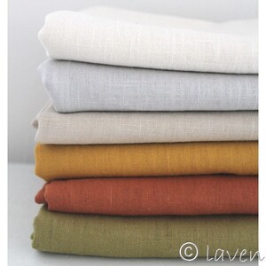 May include: Stack of five fabric swatches in different colors: white, light gray, beige, mustard yellow, and rust orange. The swatches are made of linen and have a textured surface.