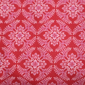 Könnte beinhalten: Roter Stoff mit einem sich wiederholenden Muster aus rosa floralen Designs. Das Muster ist kompliziert und zeigt ein zartes florales Motiv.
