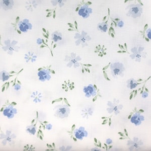 Pode incluir: Tecido branco com um padrão repetitivo de pequenas flores azuis. As flores são de estilo aquarela e têm uma cor azul claro.