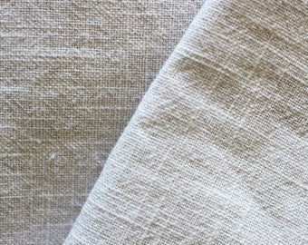 May include: Close-up of a white linen fabric with a textured weave. The fabric is folded in half, showing the texture of the weave on both sides.