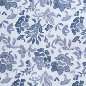 Può includere: Primo piano di un tessuto bianco con un motivo floreale ripetuto in tonalità blu e grigie. Il design presenta fiori, foglie e viti stilizzate, creando un'estetica classica ed elegante. Il motivo è distribuito uniformemente sul tessuto.
