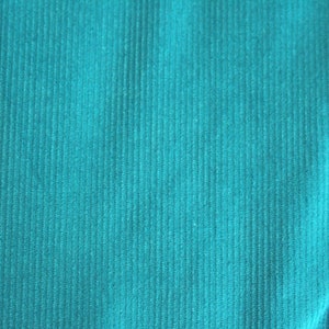 Könnte beinhalten: Nahaufnahme eines tealblauen Stoffes mit Cord-Struktur.