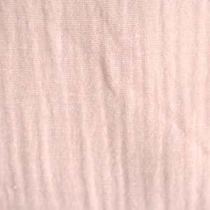 Könnte beinhalten: Nahaufnahme eines blassrosa Stoffes mit einer dezenten gewebten Textur. Der Stoff fühlt sich weich und glatt an und hat eine leicht zerknitterte Optik.