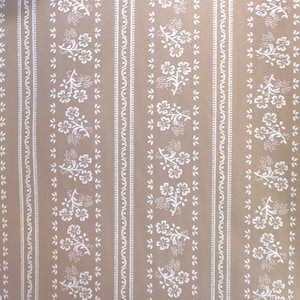 Könnte beinhalten: Eine beige Tapete mit einem sich wiederholenden Muster aus weißen Blütenzweigen und kleinen Punkten. Das Muster ist in vertikalen Streifen angeordnet.
