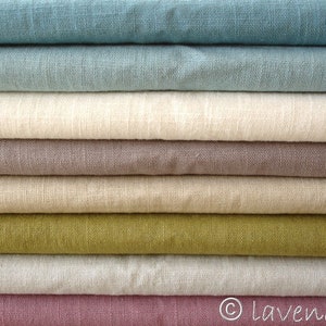 May include: A stack of eight different colored linen fabrics. The fabrics are folded neatly and arranged in a graduated color scheme, starting with a light blue and ending with a deep pink.