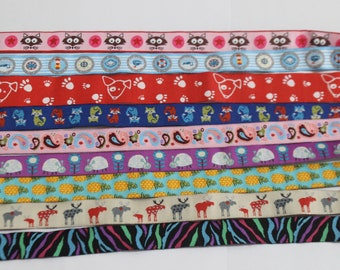 May include: Assortment of colorful patterned ribbon trims. The ribbons feature various designs, including cats, paw prints, foxes, paisley, pineapples, moose, and zebra stripes.