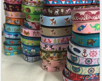 May include: A collection of colorful ribbon rolls with various patterns, including animals, mushrooms, and geometric designs. The ribbons are stacked in rows and are ready to be used for crafting projects.