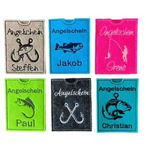 Könnte beinhalten: Sechs verschiedene Filzkartenhalter mit dem Wort "Angelschein" und verschiedenen Angelmotiven, darunter Haken, Fische und ein Angler. Die Namen "Steffen", "Jakob", "Irene", "Paul", "Christian" sind ebenfalls enthalten.