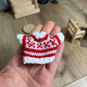 Könnte beinhalten: Ein kleiner, rot-weißer Strickpullover mit geometrischem Muster.