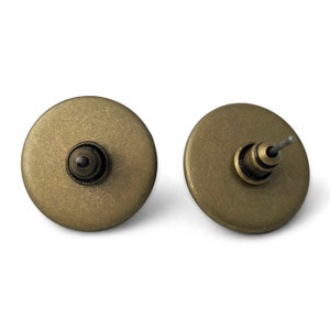 May include: A pair of antique gold-toned stud earrings with a round, flat design. The earrings have a post and butterfly backing.
