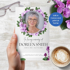 Könnte beinhalten: Gedenkkarte mit einem Foto einer Frau, umgeben von einem Kranz aus lila Blumen. Die Karte enthält den Text "In loving memory of DOREEN SMITH" und Veranstaltungsdetails. Die Karte wird von einer Hand gehalten.