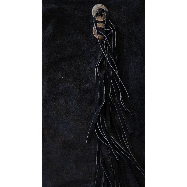 May include: Black suede skirt with a long fringe detail and three silver-toned buttons.