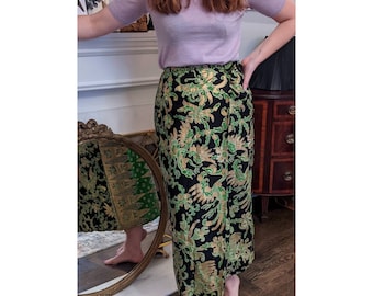 May include: A black and green wrap skirt with a gold floral pattern. The skirt is made of a silky fabric and has a flowing silhouette.