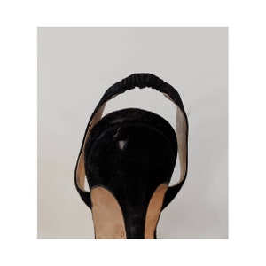 May include: Black suede heeled sandals with an open toe and a slingback strap. The sandals have a thin heel and a size 8 marked on the sole.