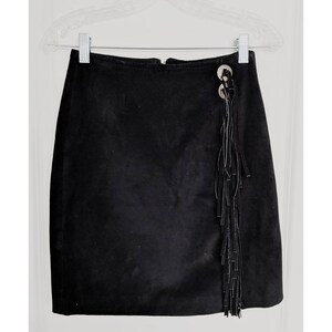 May include: A black suede mini skirt with a fringe detail and silver button accents.