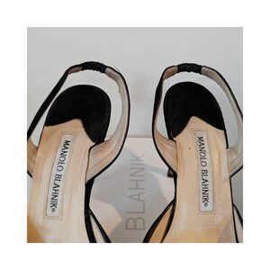 May include: A pair of black suede heeled sandals with a slingback strap. The sandals have the brand name "MANOLO BLAHNIK" printed on the insole.