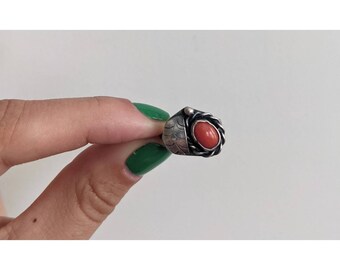 May include: A silver ring with a coral stone set in a leaf design.