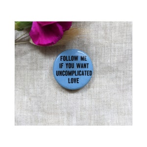 May include: A blue button with the text "FOLLOW ME IF YOU WANT UNCOMPLICATED LOVE" in black lettering.