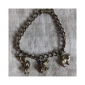 May include: A silver charm bracelet with three charms: a monkey, a camel, and an elephant with a turquoise stone. The bracelet has a silver clasp.