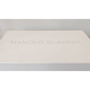 May include: A white box with the text "MANOLO BLAHNIK" printed in gray on the top.
