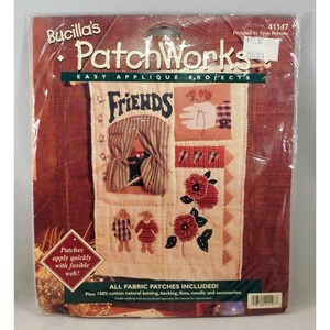 Op de afbeelding: Een Bucilla PatchWorks eenvoudig applicatieprojectpakket in plastic verpakking. De set bevat een crèmekleurig stoffen paneel met het woord Friends, stoffen patches van twee figuren, bloemen en een raam met gestreepte gordijnen. Tekst bevat all fabric patches included en patches apply quickly with fusible web.
