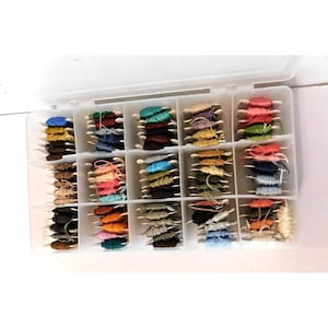 May include: A clear plastic storage container with fifteen compartments, each filled with multiple small wooden spools wrapped in embroidery floss. The collection features a wide variety of colors including blues, greens, browns, pinks, oranges, and neutrals.