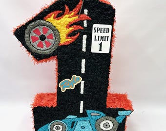 May include: A black and red number one shaped pinata with a blue racing car, a tyre with flames, and a sign that says "Speed Limit 1".