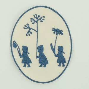 Könnte beinhalten: Ovaler, bestickter Aufnäher mit cremefarbenem Hintergrund und blauem Rand. Das Design zeigt drei Figuren, die Blumen oder Pflanzen halten. Der Aufnäher hat einen Folk-Art-Stil, mit den Figuren und Pflanzen in einem einfachen, stilisierten Design.