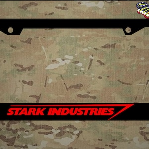 Puede incluir: Marco de matr&iacute;cula negro con un logotipo rojo "STARK INDUSTRIES". El marco tiene dos agujeros en la parte superior y dos agujeros en la parte inferior para el montaje.