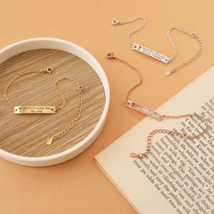 May include: Several delicate medical alert bracelets in gold, silver, and rose gold. Each bracelet features a rectangular tag with engraved text, including medical conditions and names. The bracelets are displayed on a neutral background.