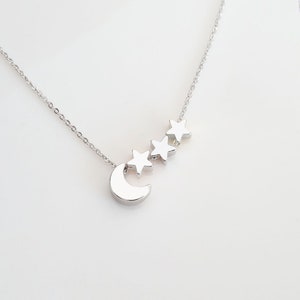 Könnte beinhalten: Eine silberne Halskette mit einem Halbmond-Anhänger und drei Stern-Anhängern.