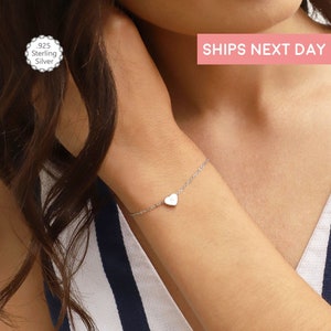 May include: A delicate silver chain bracelet with a small heart charm. The bracelet is made of 925 sterling silver.