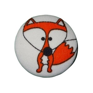 Könnte beinhalten: Ein weißer Stoffknopf mit einem Cartoon-Fuchs-Design. Der Fuchs ist orange mit einer schwarzen Nase und weißen Augen. Der Knopf ist rund und hat einen weißen Hintergrund.