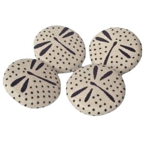 May include: Four white fabric buttons with a black polka dot pattern and a dark blue dragonfly design.