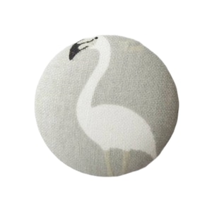 Könnte beinhalten: Ein runder, grauer Stoffknopf mit einem weißen Flamingo-Motiv. Der Flamingo ist nach rechts gerichtet und hat einen schwarzen Kopf und Schnabel.