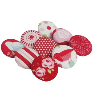 Peut inclure: Assortiment de neuf boutons recouverts de tissu dans différents motifs rouges, roses et blancs. Les boutons présentent des motifs d'oiseaux, de fleurs, de pois et de rayures.