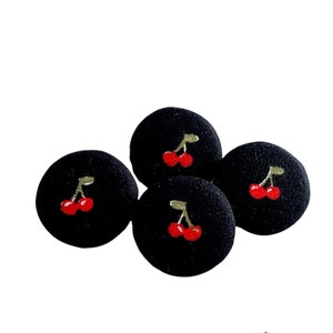 May include: Four black fabric buttons with a red cherry design. Each button has two red cherries with green stems and leaves.