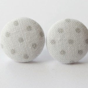 May include: A pair of white fabric stud earrings with a gray polka dot pattern.