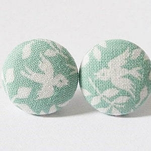 Può includere: Un paio di orecchini a bottone in tessuto verde con un motivo floreale bianco.
