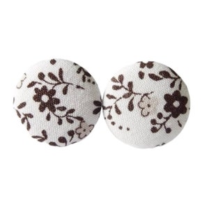 May include: A pair of white fabric buttons with a brown floral pattern.