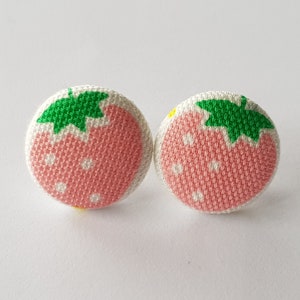 Może przedstawiać: Para różowych i zielonych kolczyków z tkaniny w kształcie truskawek w białe kropki.