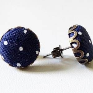 May include: A pair of blue and white polka dot fabric stud earrings with a gold-toned metal setting.