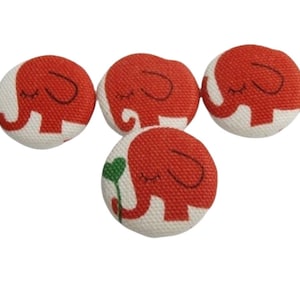 Könnte beinhalten: Vier rote Stoffknöpfe mit weißen Elefantenmotiven. Die Elefanten haben geschlossene Augen und befinden sich in verschiedenen Positionen.