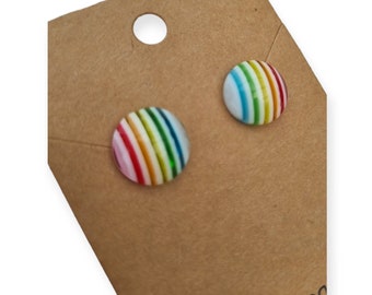 Könnte beinhalten: Ein Paar regenbogenfarbene Ohrstecker. Die Ohrringe sind rund und haben einen weißen Hintergrund mit bunten Streifen.
