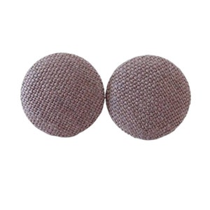May include: A pair of round, mauve fabric earrings. The earrings are made of a textured fabric.
