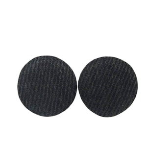 Może przedstawiać: Dwa czarne, okrągłe podkładki filcowe. Podkładki mają fakturowaną powierzchnię.