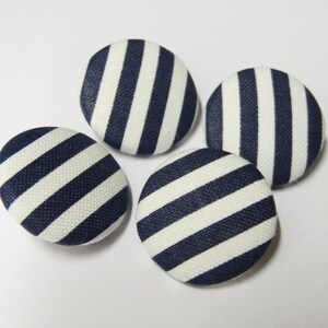 Peut inclure: Quatre boutons ronds en tissu avec un motif rayé blanc et bleu marine.