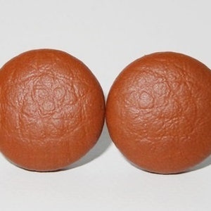 Könnte beinhalten: Ein Paar runde Ohrstecker aus braunem Lederimitat.