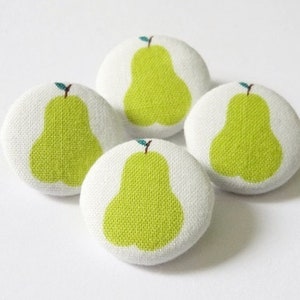 Könnte beinhalten: Vier weiße Stoffknöpfe mit grünen Birnenmotiven. Jeder Knopf hat eine grüne Birne mit einem kleinen braunen Stiel und einem grünen Blatt.