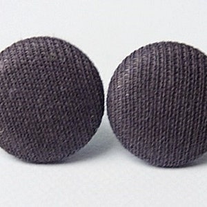 May include: A pair of dark gray fabric button earrings. The buttons are round and have a textured surface.